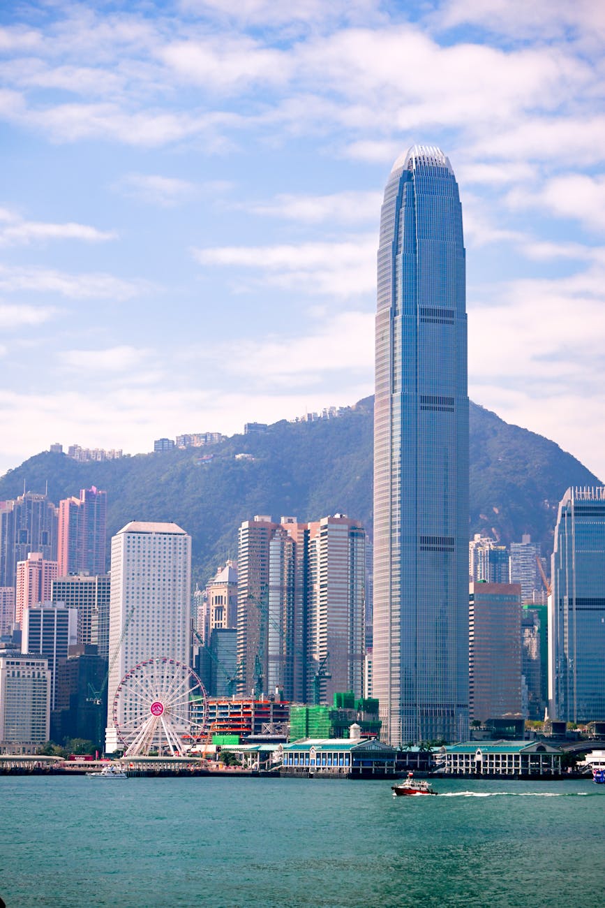 Stunning view of Hong Kong’s skyline featuring the IFC tower and a ferris wheel under a summer sky. Stunning view of Hong Kong’s skyline featuring the IFC tower and a ferris wheel under a summer sky.