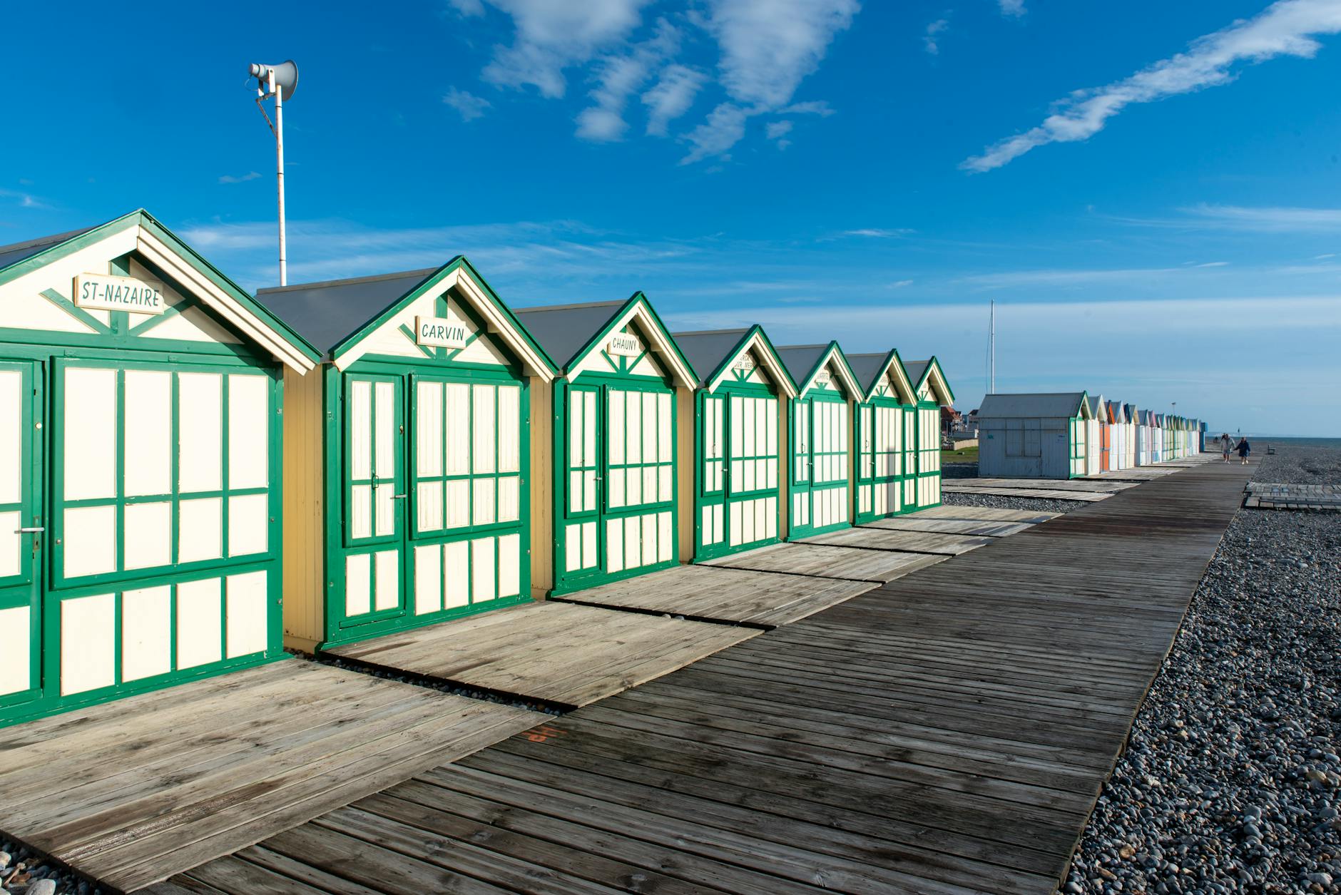 Charming beach cabins near the sea under a bright blue sky, perfect for summer vacations.