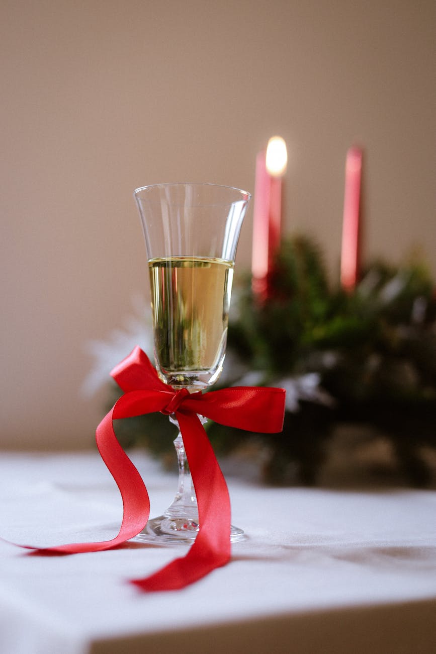 A champagne glass adorned with a red ribbon in a festive setting, ideal for holiday celebrations. A champagne glass adorned with a red ribbon in a festive setting, ideal for holiday celebrations.