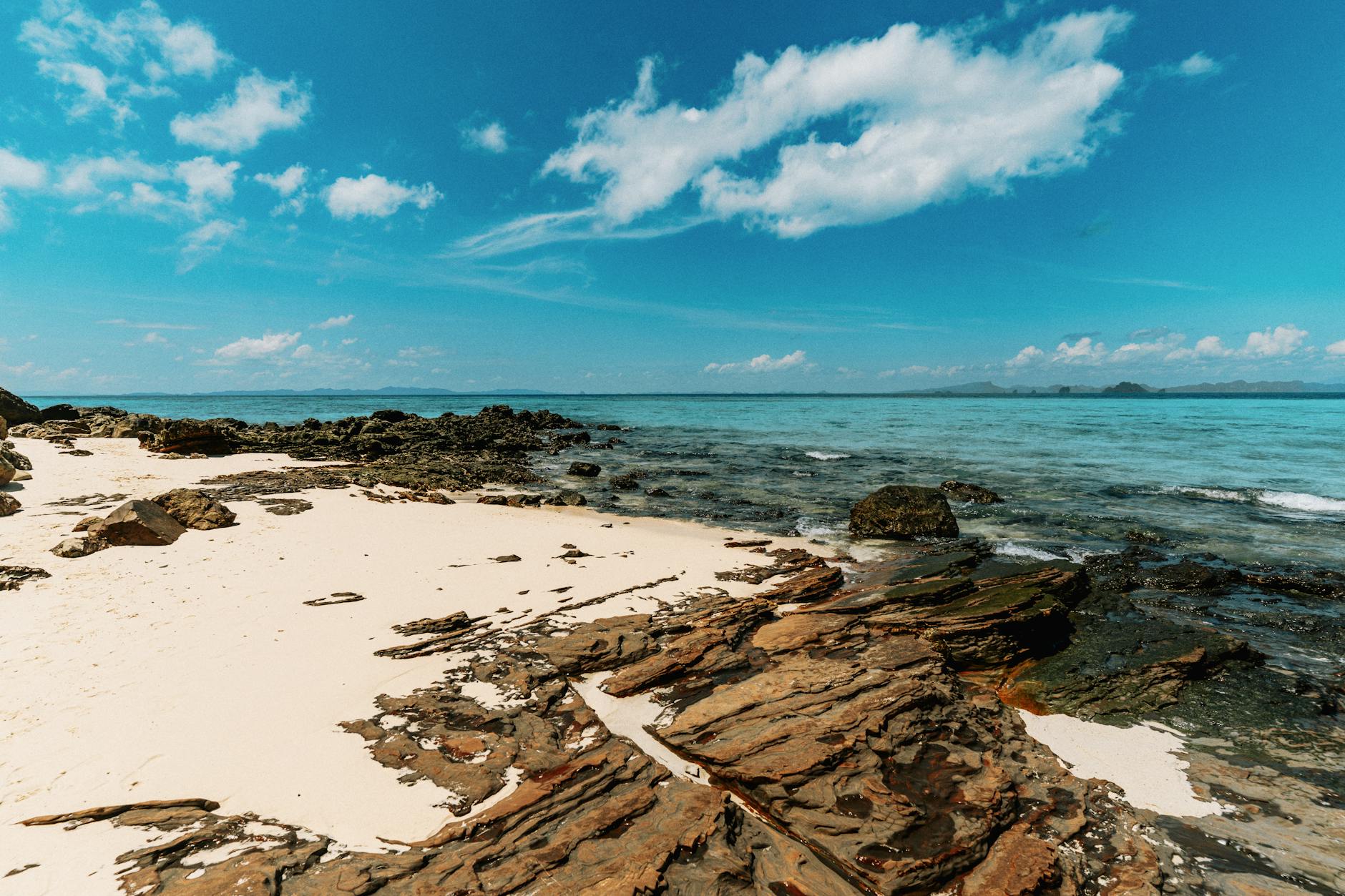 A picturesque beach in Ao Nang, Thailand, showcasing clear skies and vibrant blue waters.