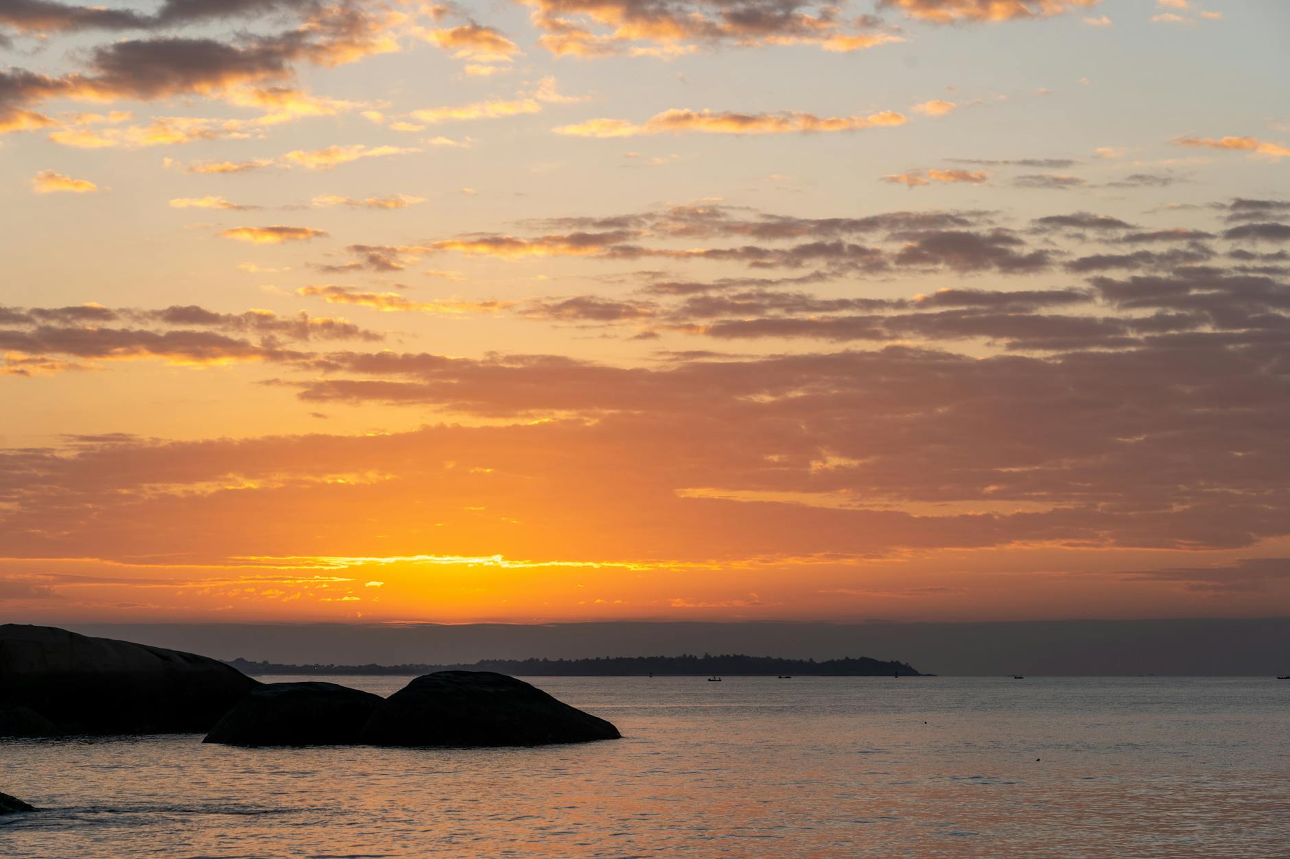 A serene sunset over the ocean with silhouetted rocks in the foreground, creating a peaceful ambiance. A serene sunset over the ocean with silhouetted rocks in the foreground, creating a peaceful ambiance.