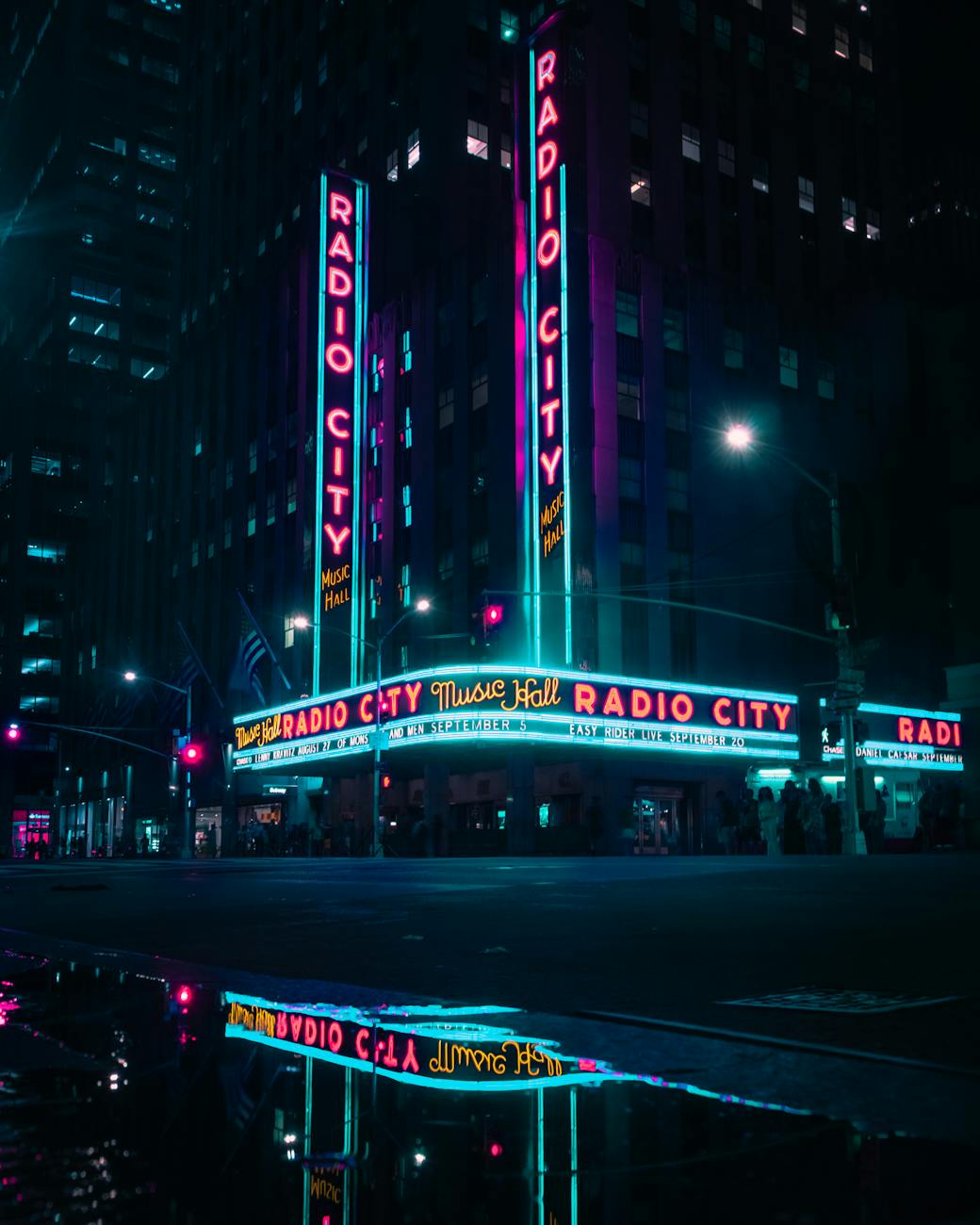 Vibrant nighttime view of Radio City Music Hall with neon lights and reflections.