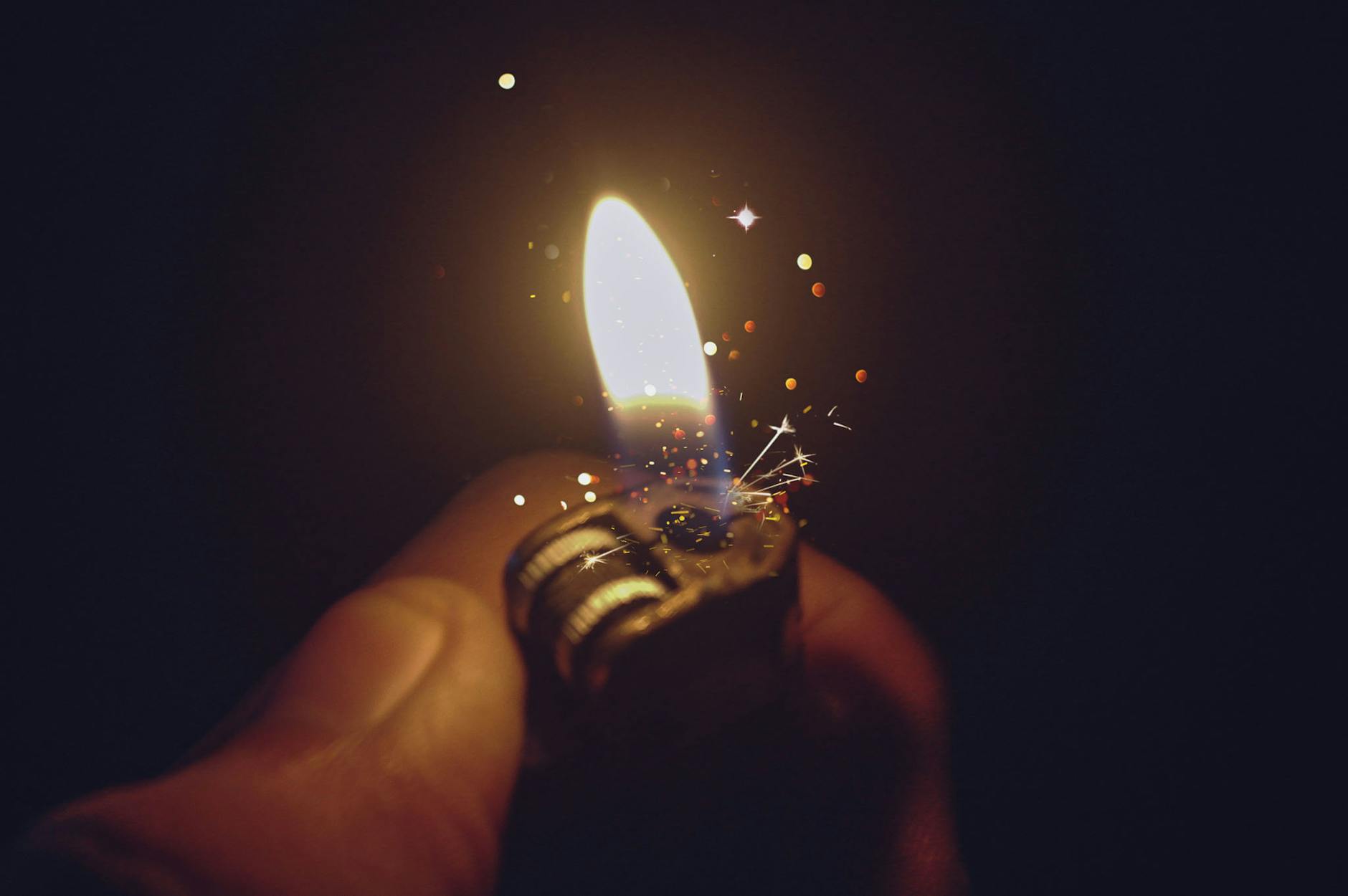 Intense close-up of a lighter igniting a bright flame with spark effects against a dark background. Intense close-up of a lighter igniting a bright flame with spark effects against a dark background.
