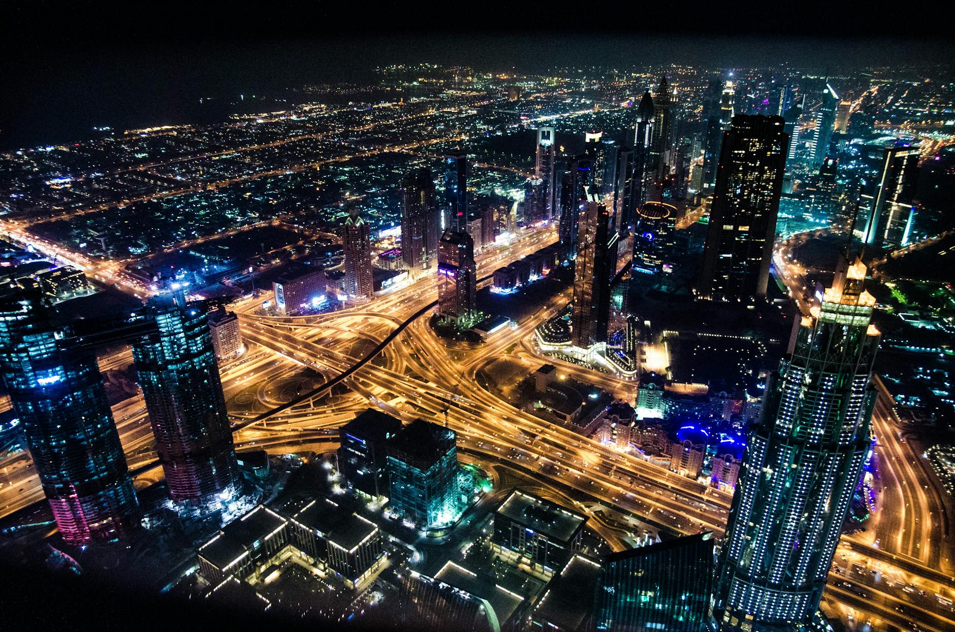 A stunning aerial view of Dubai’s illuminated skyline at night, showcasing its modern architecture and busy roads.
